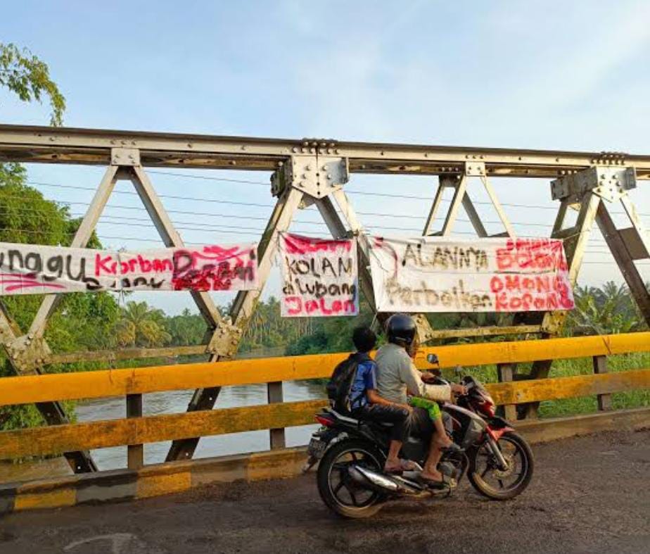 Jalan Berlobang Tak Kunjung Diperbaiki, Warga Pasang Spanduk di Jembatan Rawa Makmur 